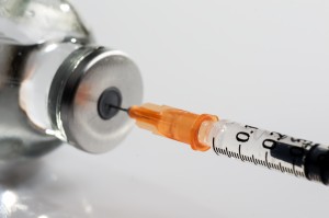 syringe drawing out vaccine from bottle